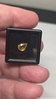 Yellow sapphire in display case held between fingers