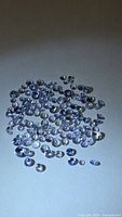 Group of small round faceted violet-blue tanzanite stones on white background