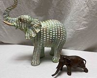 Both elephant figurines side by side showing size and material contrast