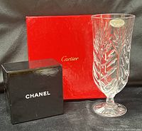 Crystal vase with Fifth Avenue label beside Cartier and Chanel boxes
