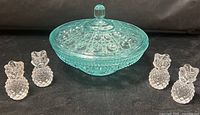 Group shot showing four clear glass pineapple candle holders and aqua lidded bowl