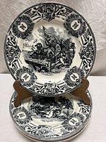 Two plates on stand showing border design and central battle illustration