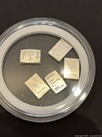 Five 1-gram silver bars inside round plastic capsule