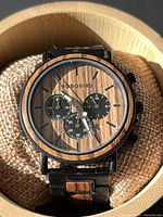 Front view of watch showing wood bezel, dial, chronograph subdials, hands and brand name