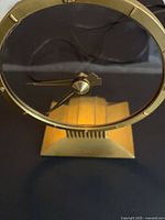 Front view of Jefferson Golden Hour mystery clock showing clear dial, gold frame, stepped base, power cord visible