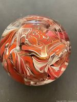 Top view of spherical glass paperweight showing multicolour swirl interior