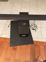 Sound bar spanning above subwoofer on tiled floor