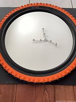 Front view of round mirror with orange BMX tire frame