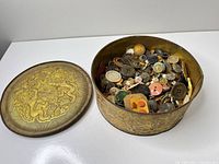 Tin with lid removed showing assorted buttons