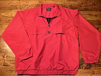 Full front view of red Descente pullover laid flat, showing long sleeves and elastic hem