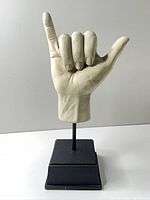 Front view of off-white hand sculpture on black base