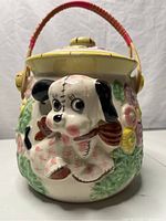 Front view showing 3-D puppy, lid, handle