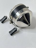 Angled view of Zebco 33 reel showing chrome nose cone, brand mark, dual handles