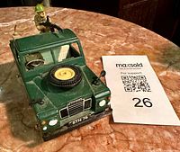 Front three-quarter view showing Land Rover, bonnet spare tire, soldier gunner, driver, and QR card