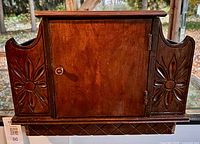 Front view showing door, carvings, diamond lattice base