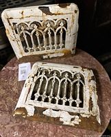 Two square cast iron vent grates with Gothic tracery, flaking paint, rust patina