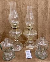 All four glass oil lamp pieces showing two assembled lamps and two bases