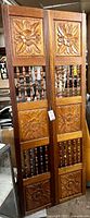 Full view of bi-fold door showing carved floral panels and spindle sections