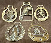Front view of five brass harness medallions