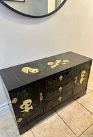 Front and top view of black lacquer cabinet showing panda artwork and drawer layout