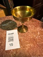 Full view of brass chalice on table with tag