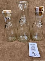 Group shot of three clear glass milk bottles showing sizes and corks