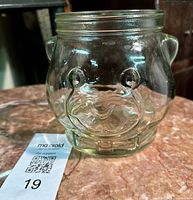front view of clear glass jar showing embossed bear face and ear handles