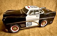 Left side view of black and white tin police car showing police shield graphic and number 104