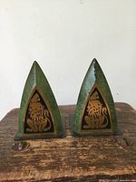 Front view of both enamelled metal bookends showing green finish and lion motif