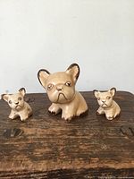 Frontal view of all three ceramic dog figurines on wooden surface
