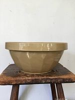 Side view of tan glazed Medalta stoneware mixing bowl on stool
