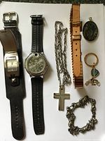 All items laid out: two watches, chain with cross, watch strap, cameo pendant, keyring, charm bracelet