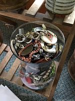 Top view of glass vase showing tangled earrings, pendants and chains