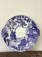 Front of plate displaying blue oriental scene pattern and scalloped rim