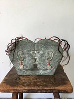 Front view showing entire soapstone two-face sculpture with hair and coin earrings