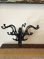 Front view of ornate black cast iron collapsible wall hanger fully opened