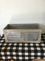 Front of wooden crate showing metal louvered panel