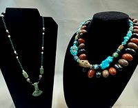 Full view showing green stone pendant necklace on left and two necklaces on right stand
