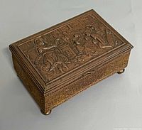 Closed box angled view showing exterior sides, lid detail, ball feet