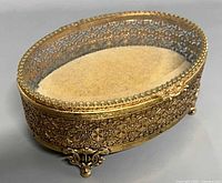 Closed view of oval brass filigree jewelry casket on scrolled feet