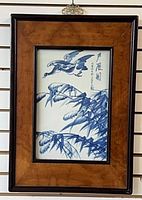 Front view of framed blue and white porcelain plaque showing bird and bamboo design