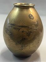 Front view of brass vase showing hand-chased mountains, pagoda and trees