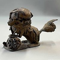 Side view of bronze foo dog with paw on orb