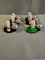 Front view of six matching butler figurines with cloches
