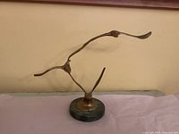 Front view of brass bird sculpture showing overall form and marble base