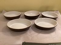 Five oval brown and white ceramic dishes top view