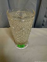 Full view of clear pressed glass vase with diamond-point surface and scalloped rim