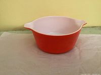 Side view of orange Pyrex casserole showing exterior color and handle shape
