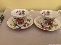 Two Royal Albert Flower Basket teacups on matching saucers