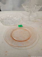 Group shot of three glass pieces: divided dish, pedestal bowl, pink plate